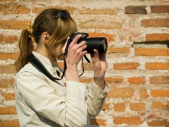 A woman taking digital photographs with a digital camera and using tips for taking great digital photograph.