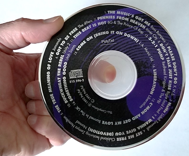 A music CD being handled properly. Handle a CD, DVD, or Blu-ray disc with your index finger at the hub and thumb on the outer edge to avoid fingerprint contamination.