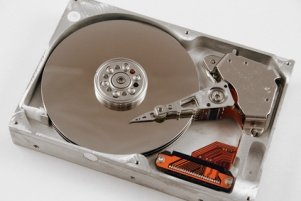 A modern opened internal hard drive. Note the the chrome colored disk platter and the various components to make the drive function such as the disk head arms.